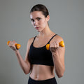 Woman exercising with yellow dumbbells against a gray background
