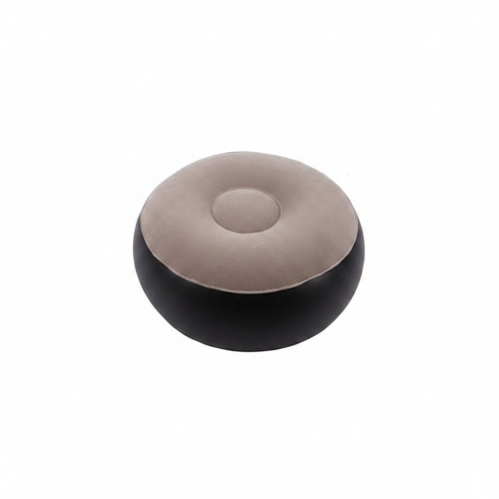 A round, low-profile pouf ottoman with a two-tone design, featuring a light taupe-beige top cushion and a black base, shown against a plain white background.