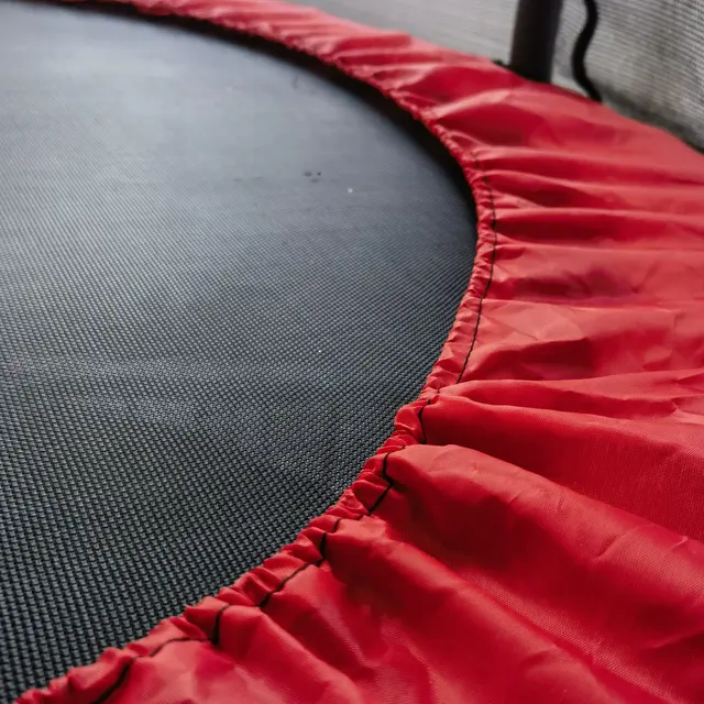 Close-up of a red trampoline rim with black surface