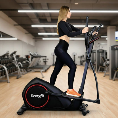 A woman in a black athletic outfit and orange sneakers is using a black elliptical trainer with red accents. The image has a white background, a gray floor, and text overlays including 'UPC : 00215' and a logo in the top left corner.