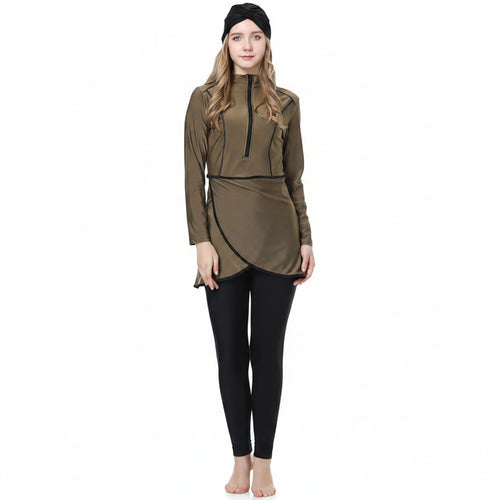 A woman modeling a long-sleeve olive green athletic top with a half-zip neckline and black trim, paired with black leggings and a black beanie, against a plain white background.