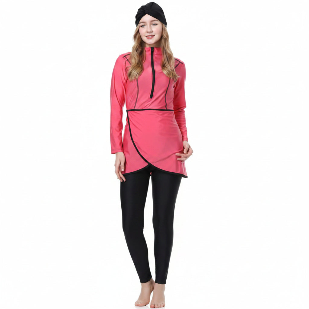 A woman modeling a pink long-sleeve swim dress with black trim and black leggings, standing against a plain white background.