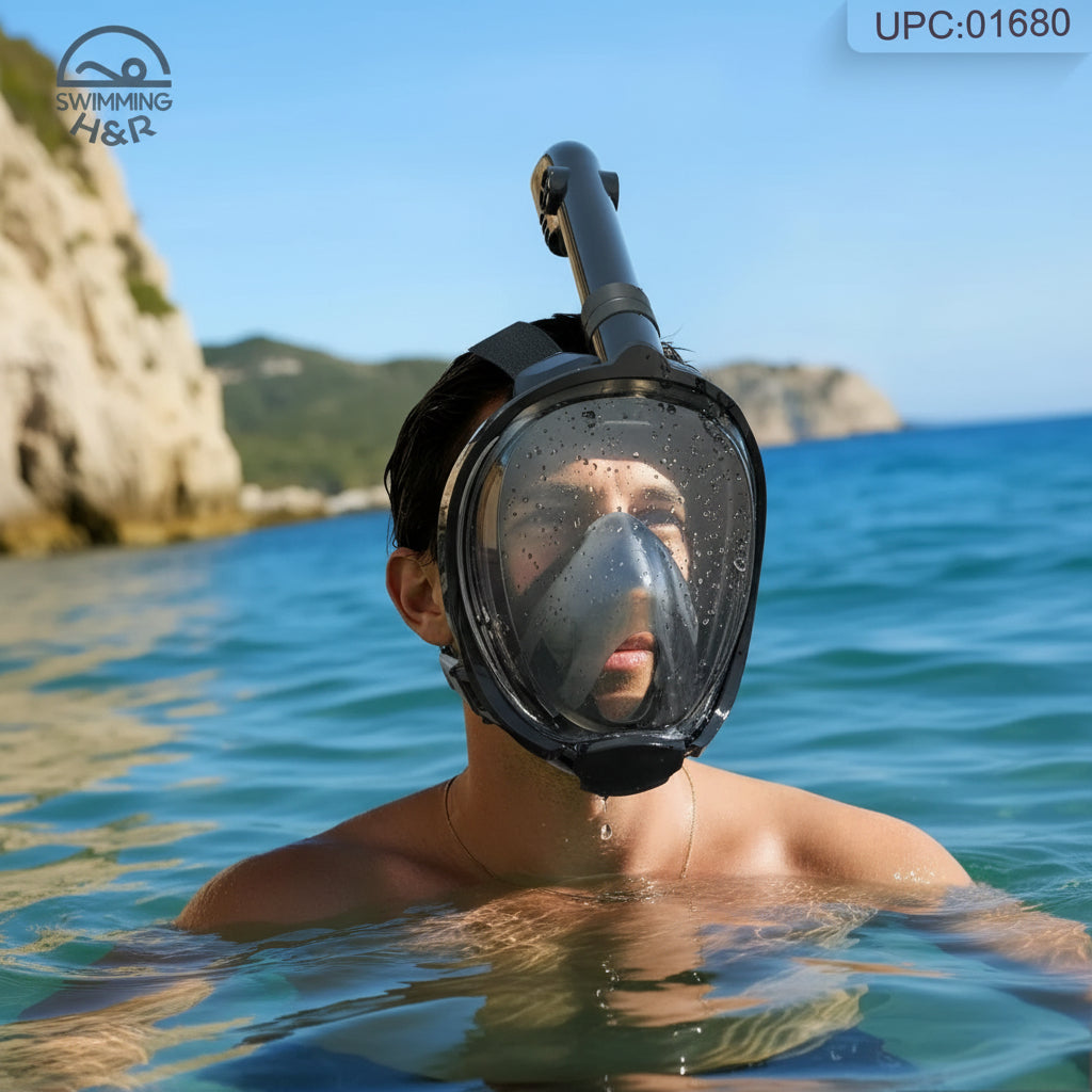 A man wearing a full-face snorkeling mask and tube, swimming in the ocean with rocky cliffs and blue sky in the background. A 'Swimming Gear' logo is visible in the top-left corner.