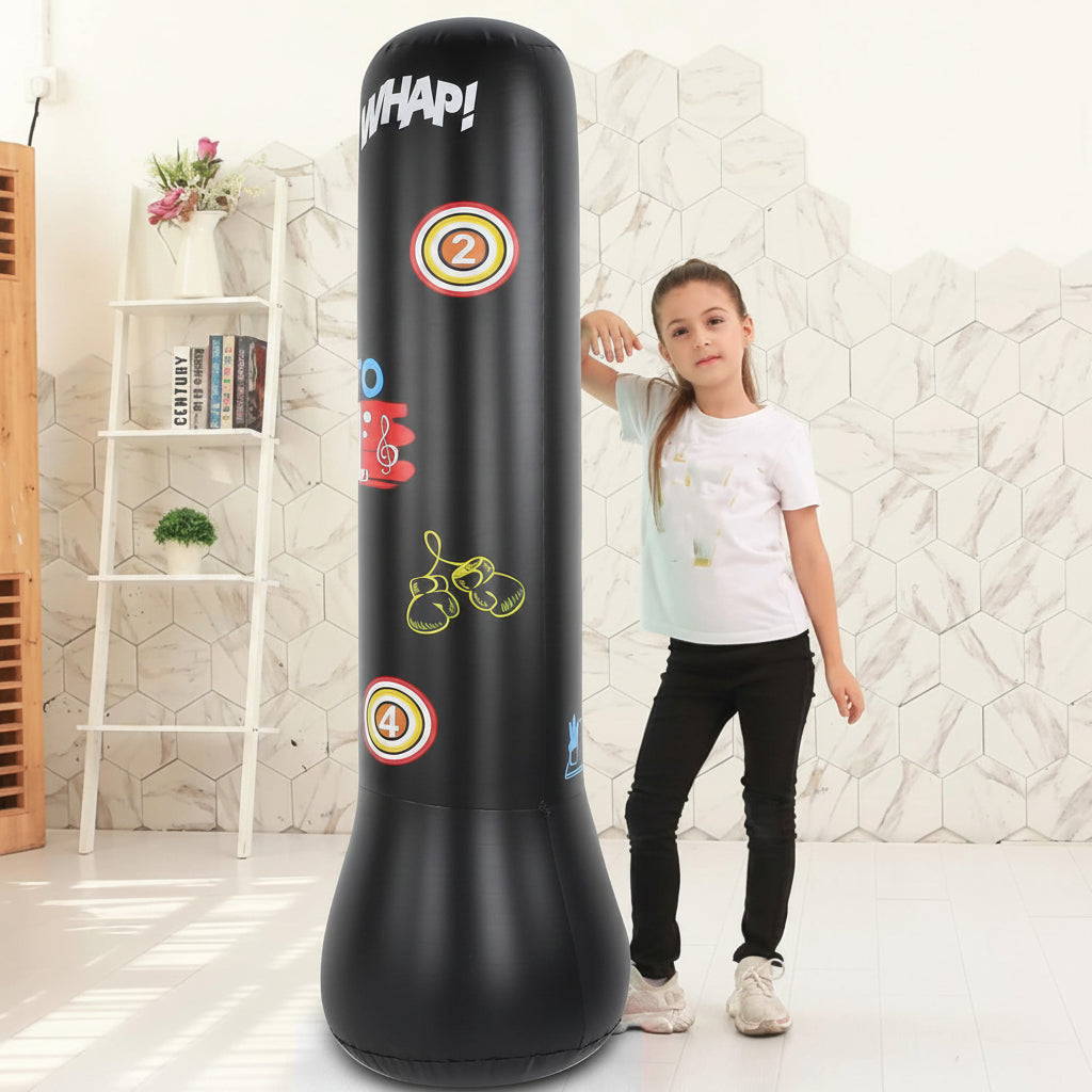 A young girl stands next to a large black inflatable punching bag with colorful target graphics and the word 'WHAP!' printed on it, set in a bright, modern room with a white geometric wall.