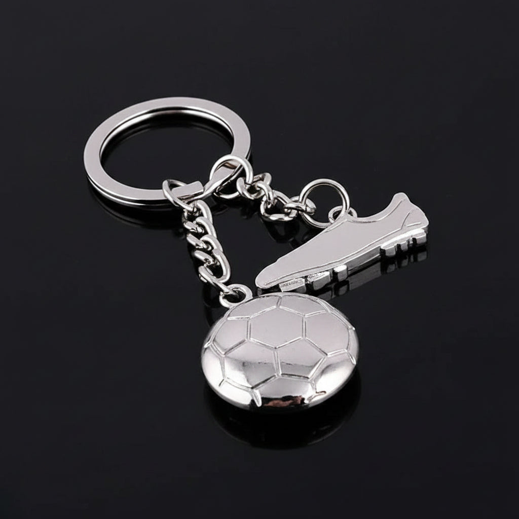 Silver keychain with soccer ball and cleat design on a black background