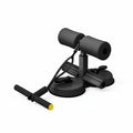 A black foam exercise device with suction cup base and a T-bar handle with a yellow accent, shown on a light wood floor in a bright room.