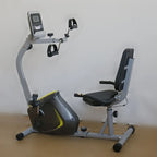 Recumbent exercise bike on a wooden floor with a white wall background