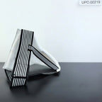 A white fabric bag with bold black and white vertical stripes on its edges, displayed on a dark surface next to a small hexagonal sign on an easel.