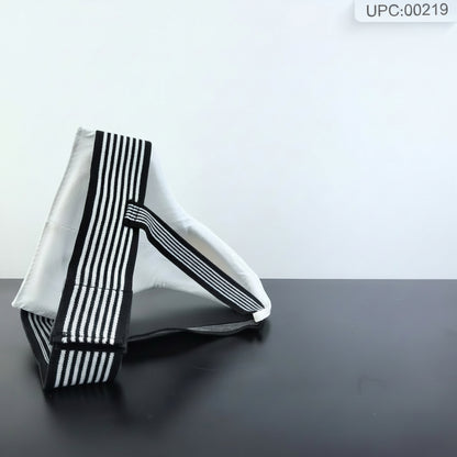 A white fabric bag with bold black and white vertical stripes on its edges, displayed on a dark surface next to a small hexagonal sign on an easel.