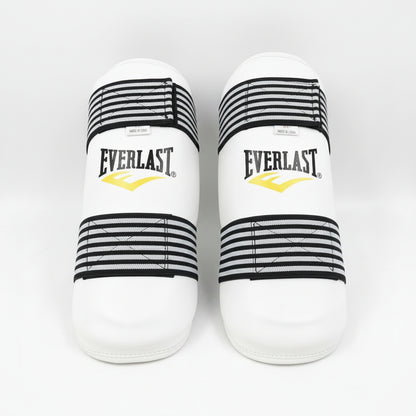 A pair of Everlast boxing shin guards in white with black and white striped elastic
