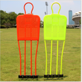 Two colorful training markers on a grassy field with buildings in the background