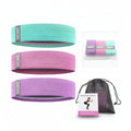 Set of resistance bands in green, pink, and purple with a drawstring bag on a white background.