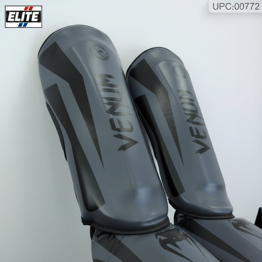 A pair of Venum shin guards in dark gray and black, shown against