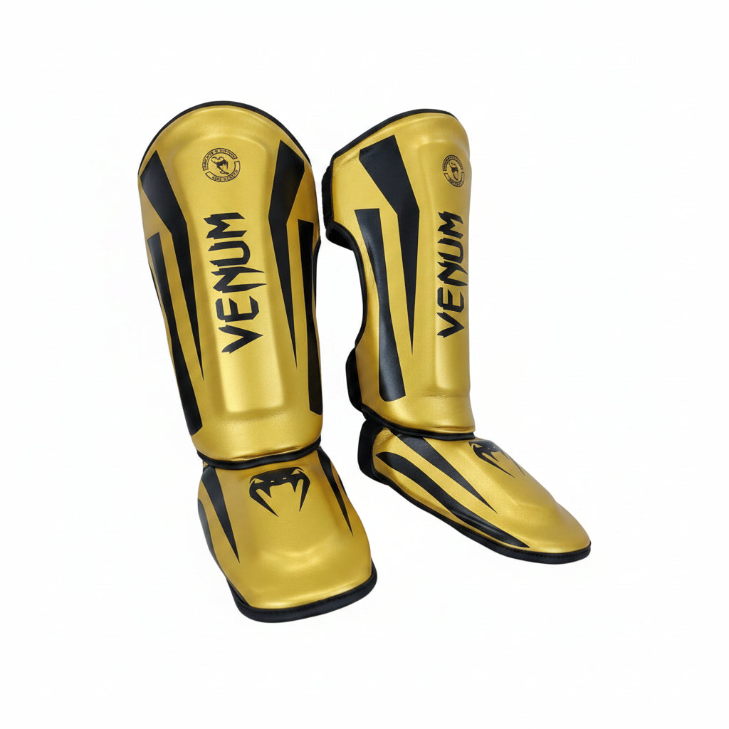 A pair of gold and black Venum shin guards displayed 